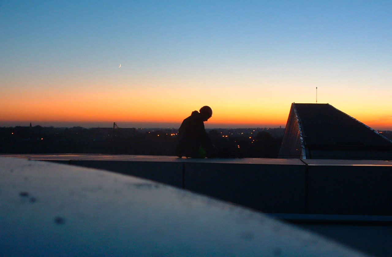 travailleur en hauteur sur une toiture au lever du jour